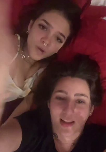 Mel Maia e amiga deitada na cama gravando tiktok